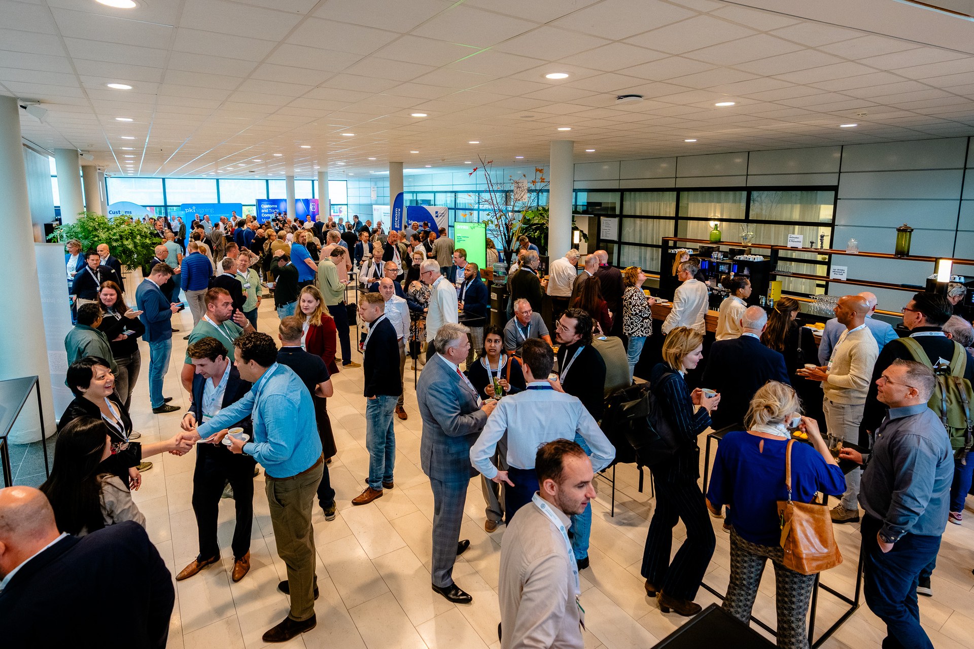 Ontmoetingen tussen bezoekers in de lichte foyer van De Doelen. Nationaal Douanecongres 2026, Rotterdam. Fotografie: Leroy Beesemer, in samenwerking met Youngblood Productions.