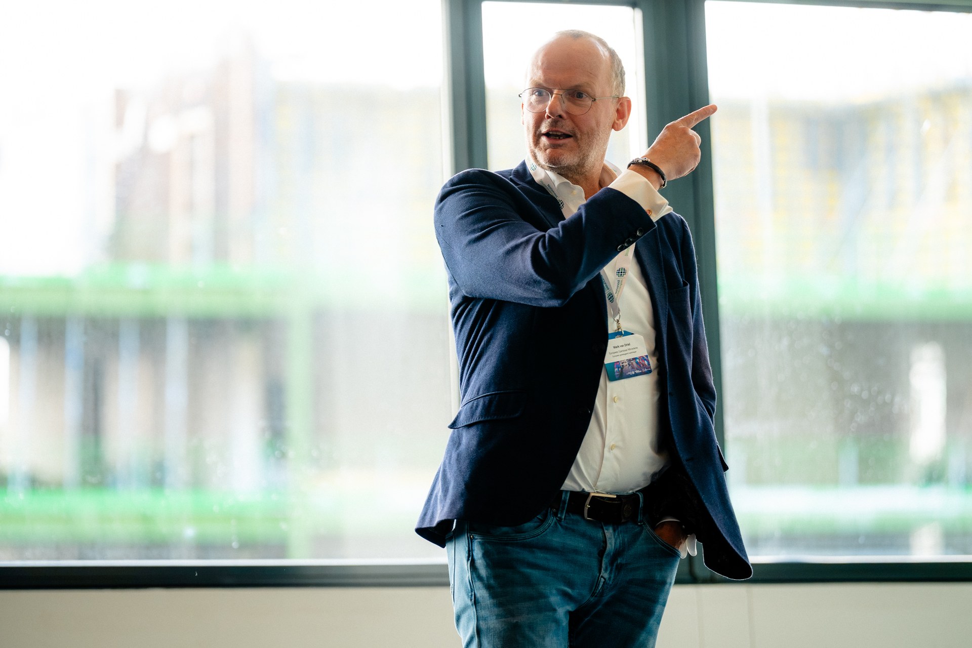 Spreker tijdens een deelsessie met daglicht en zicht op Rotterdam. Nationaal Douanecongres 2026, Rotterdam. Fotografie: Leroy Beesemer, in samenwerking met Youngblood Productions.