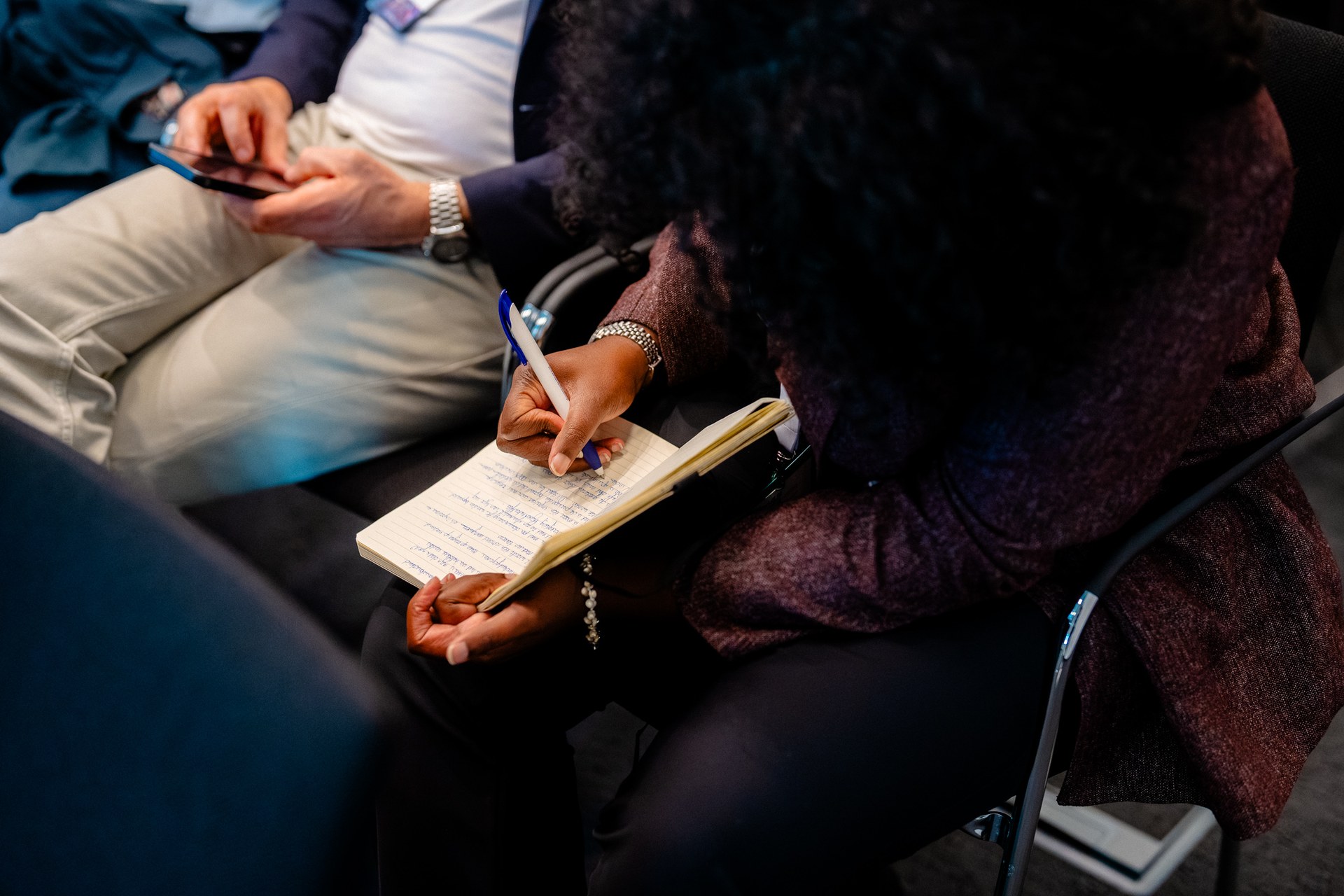 Detail van een bezoeker die aantekeningen maakt. Nationaal Douanecongres 2026, Rotterdam. Fotografie: Leroy Beesemer, in samenwerking met Youngblood Productions.